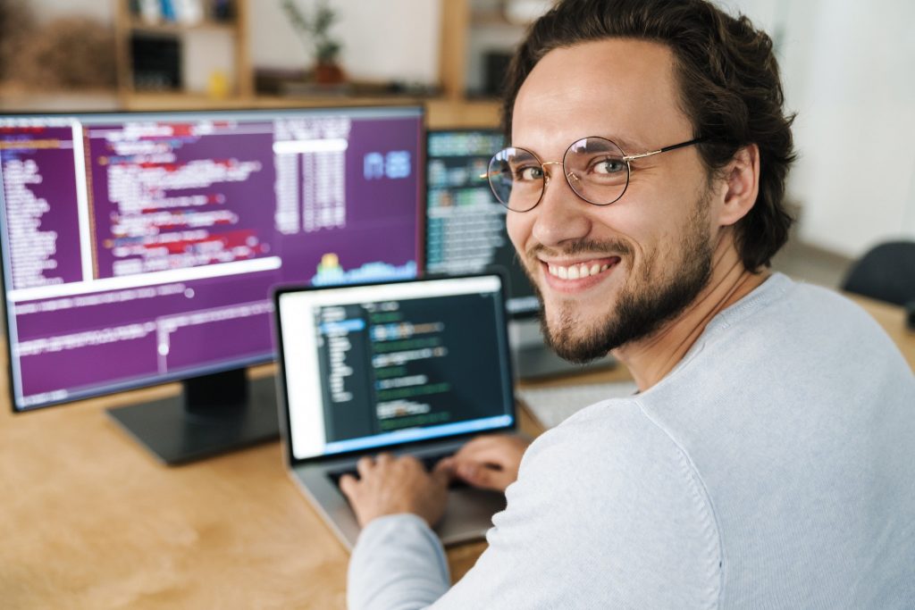 Image of programmer man wearing eyeglasses working with computers